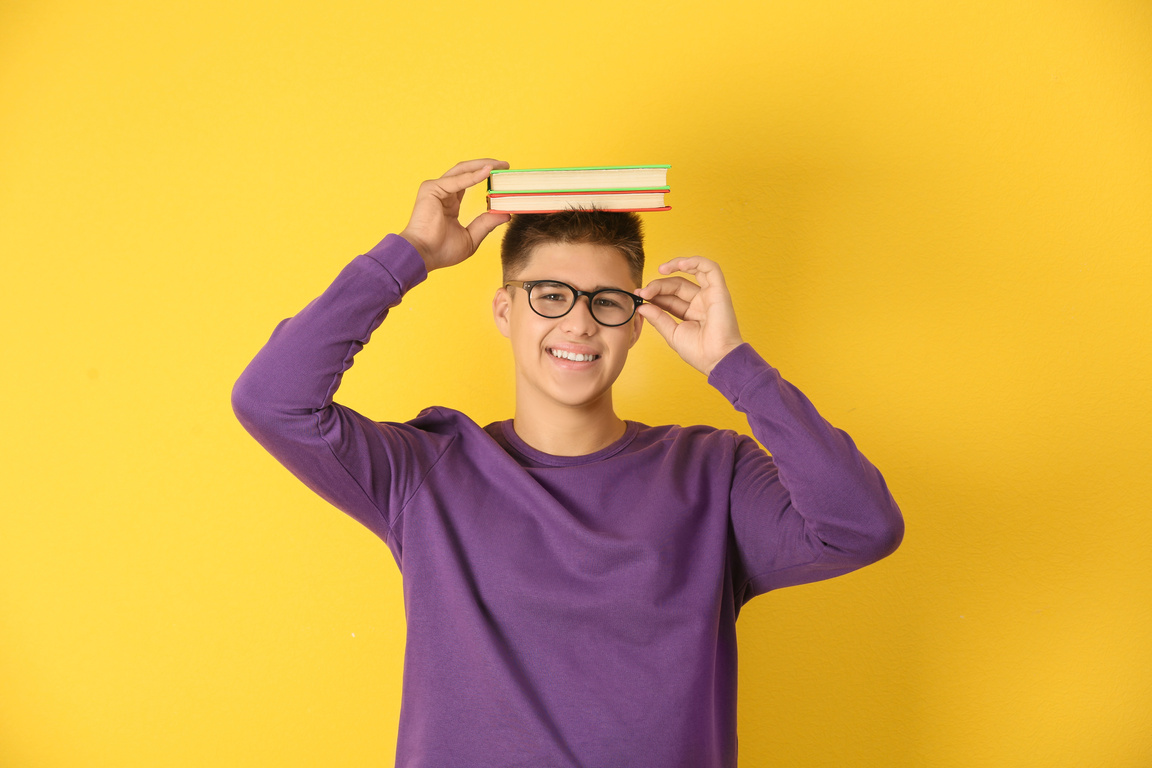 Teenager Boy with Eyeglasses Holding Books on His Head